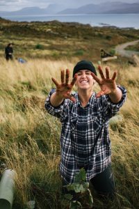 Volunteer who has been working outdoors holds up muddy hands to camera.